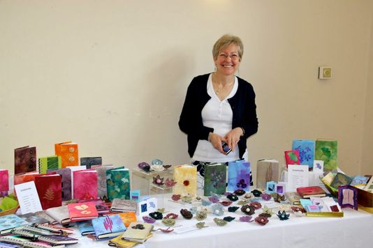 Picture of Maria Tufft standing behind her stall of fabric creations - notebooks and corsages